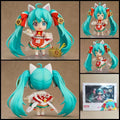 Hatsune Miku Maneki Miku chibi action figure with turquoise twin-tails, lucky cat ears, red-and-white outfit, lucky charm accessories, and clear display base.